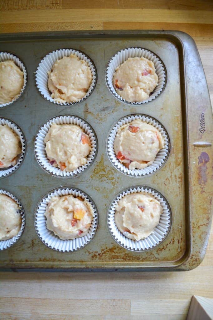 Muffin batter scooped into a lined muffin tin