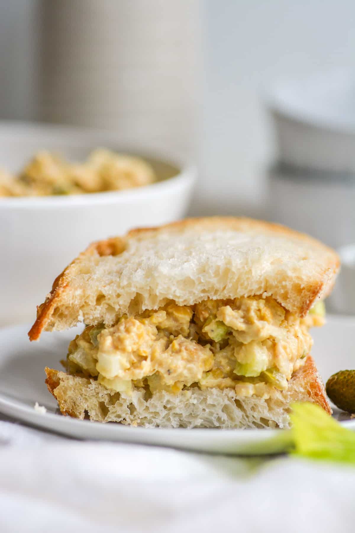 Vegan Chickpea Egg Salad on a sandwich on a white plate.