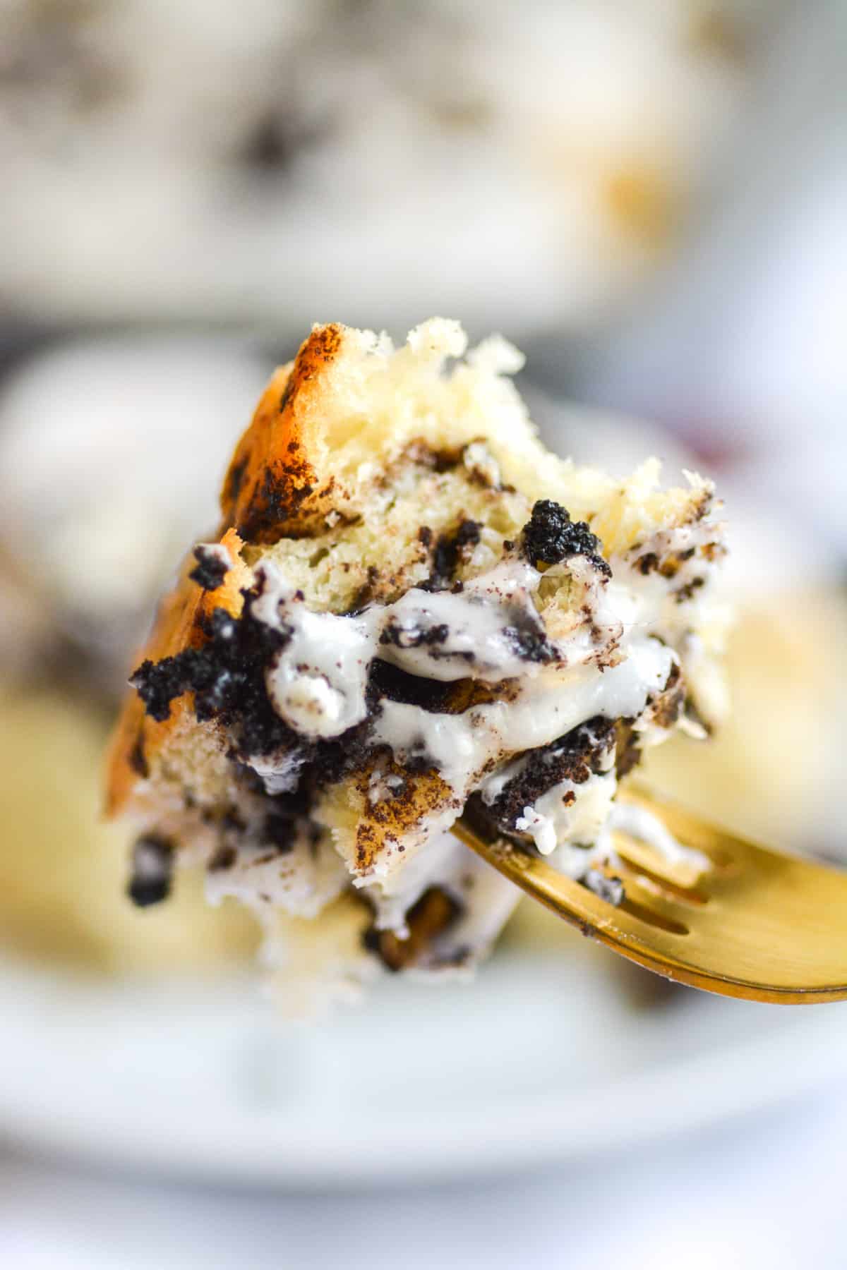 a bite of vegan oreo cookie stuffed cinnamon roll on a gold fork.