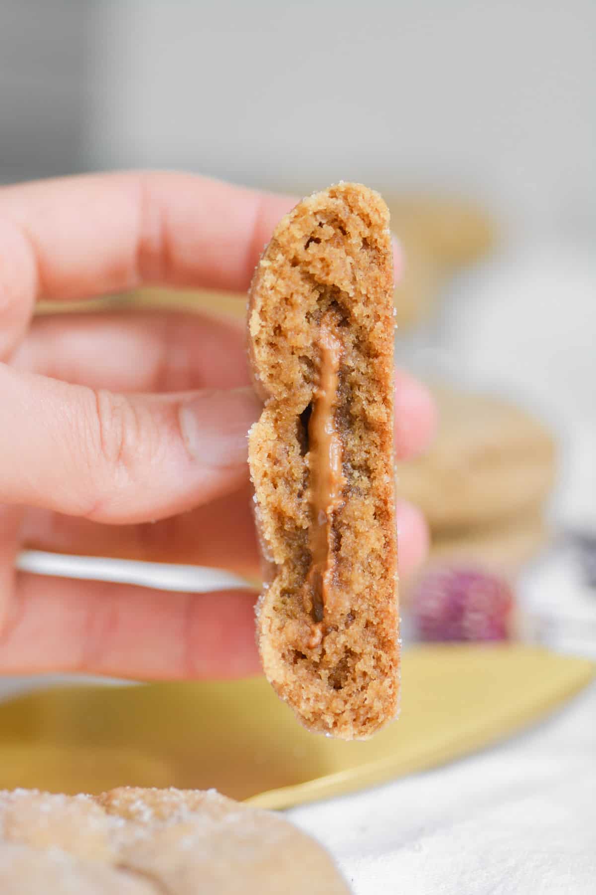 Hand holding a broken open Biscoff stuffed cookie to show the cookie butter filling