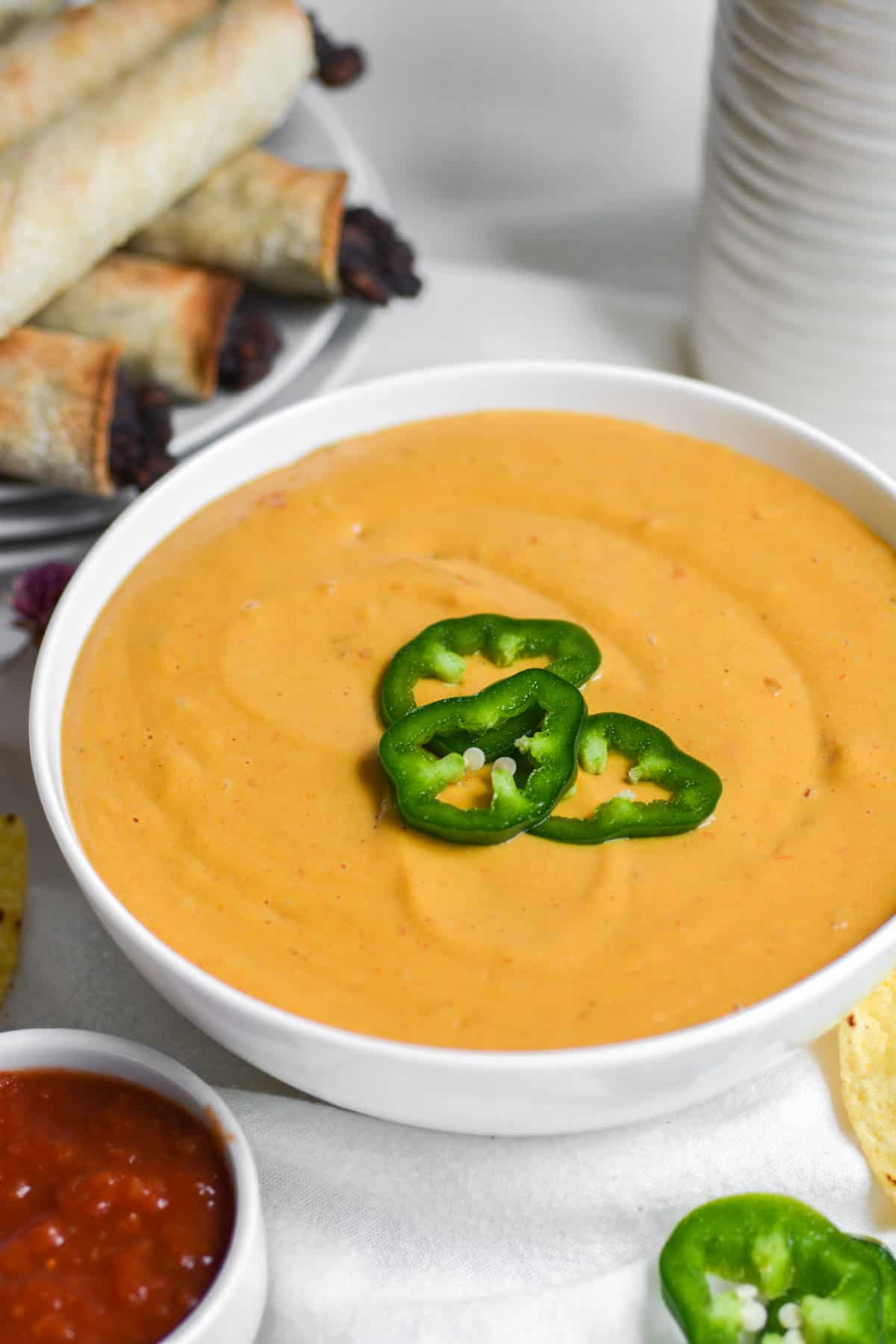 A white bowl with nut free vegan rotel dip topped with sliced jalapenos