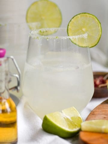straight-on shot of a sparkling margarita with a lime salt rim.