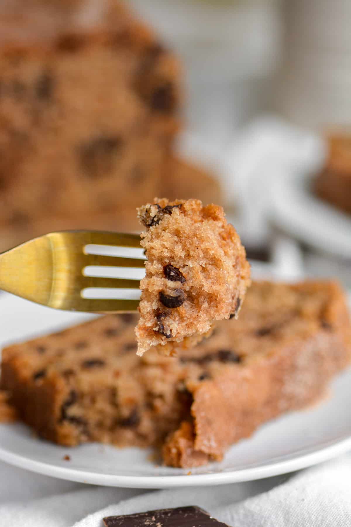 A bite of Vegan Cinnamon Chocolate Chip Bread loaf on a gold fork