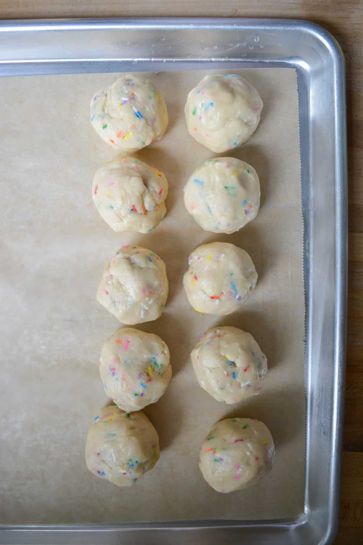 Scooped cookie dough rolled into balls on a baking sheet.