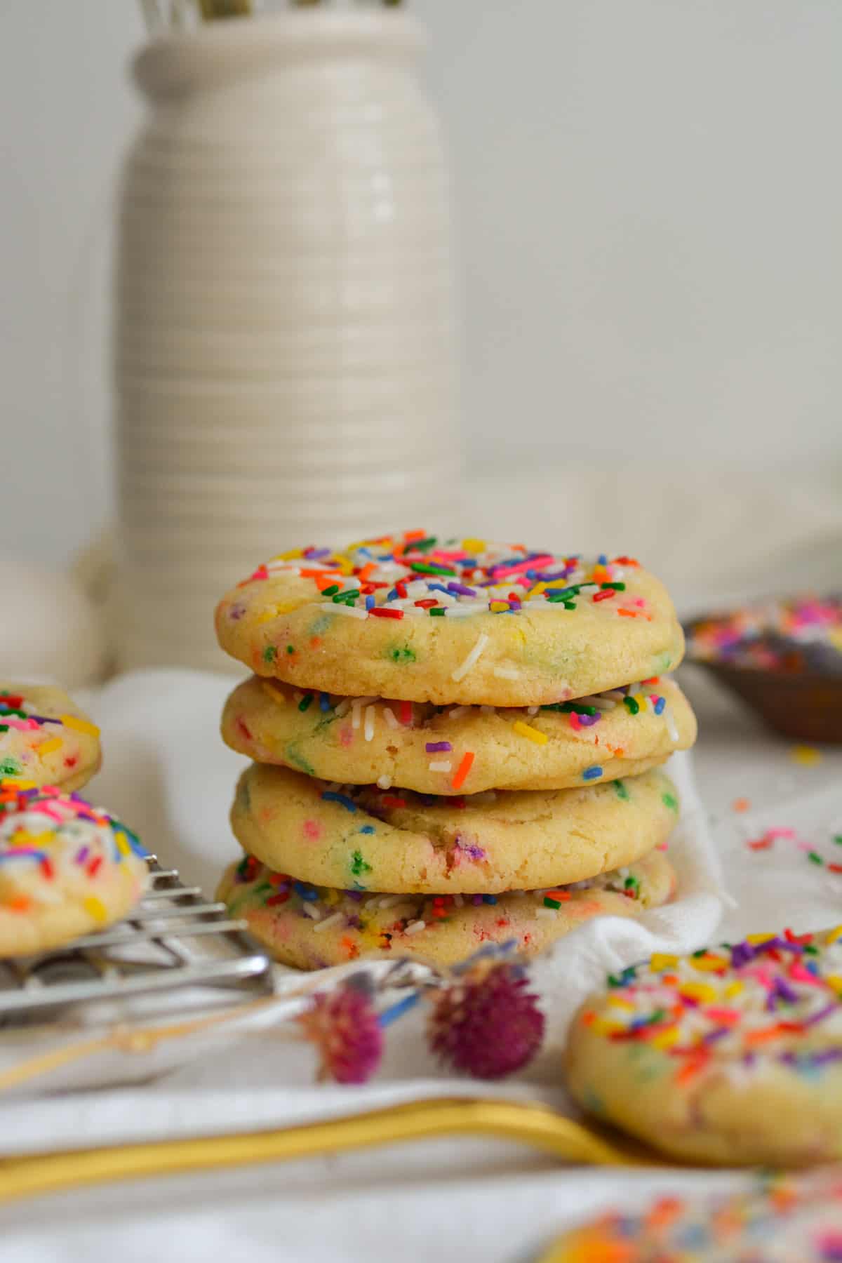 A stack of 4 vegan sprinkle cookies on a white cloth