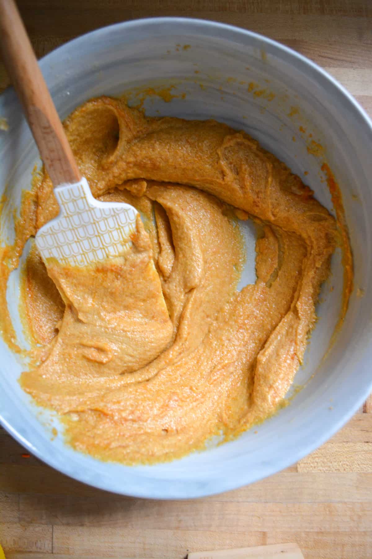 Pumpkin puree mixed into the vegan butter and sugar mixture in a marble bowl