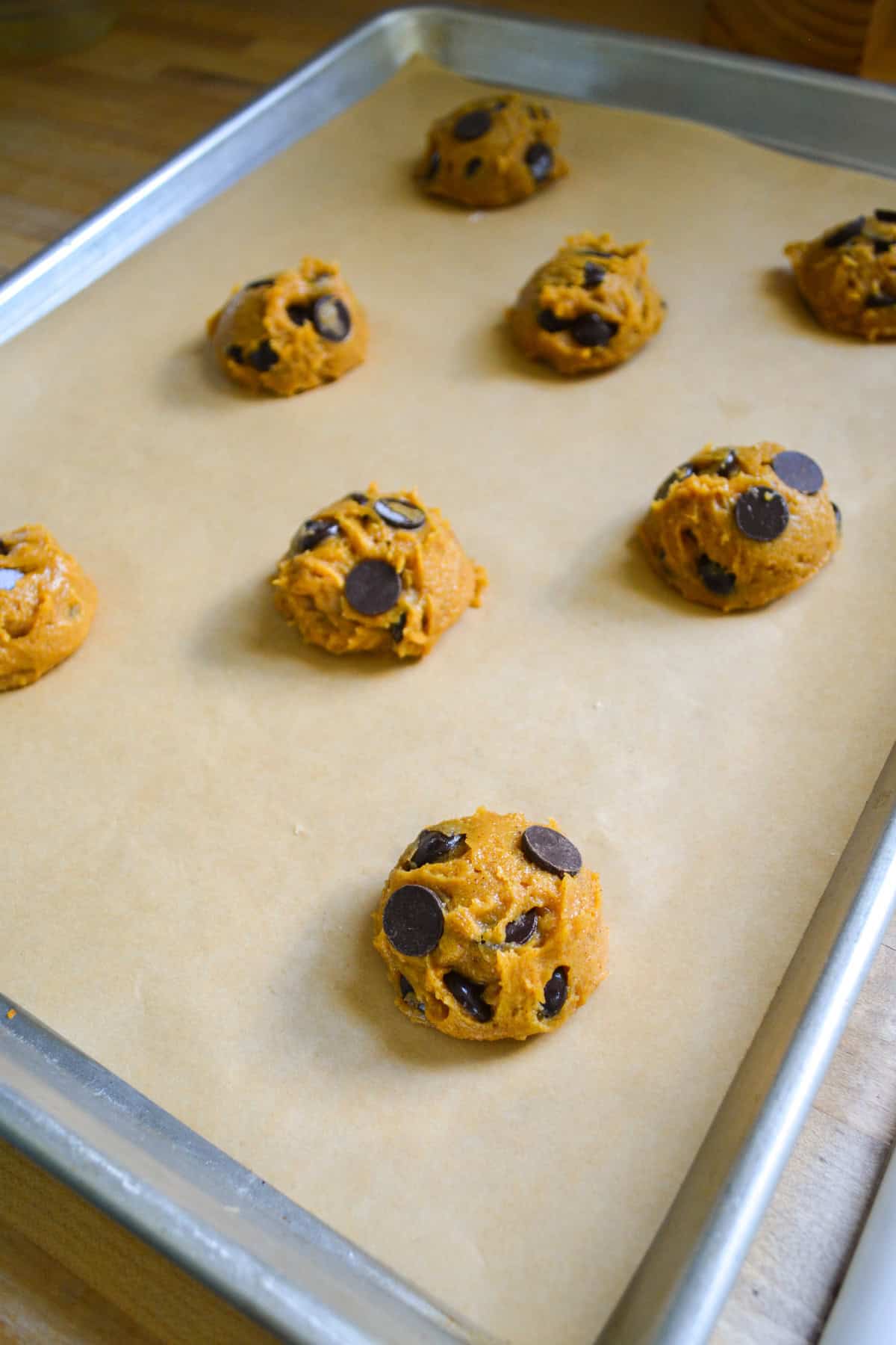 Cookie dough scooped onto a parchment-lined baking sheet.