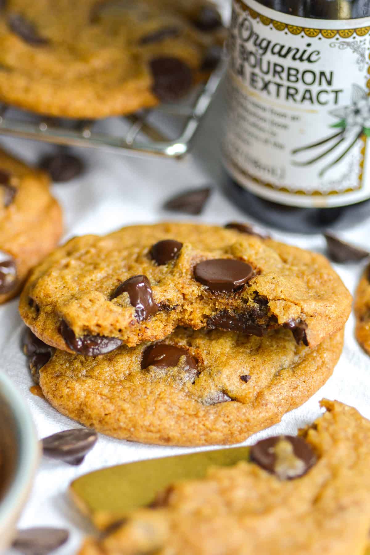 A Vegan Pumpkin Chocolate Chip Cookie with a bite taken out of it on top of another cookie.