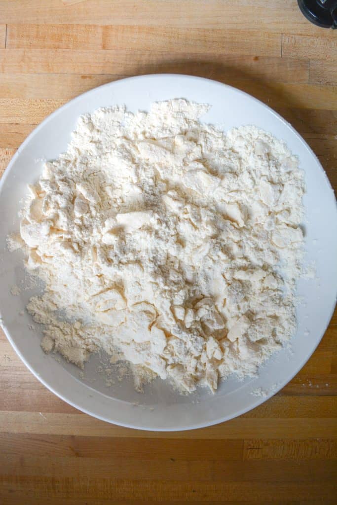 vegan butter cut into dry ingredients in a white bowl.