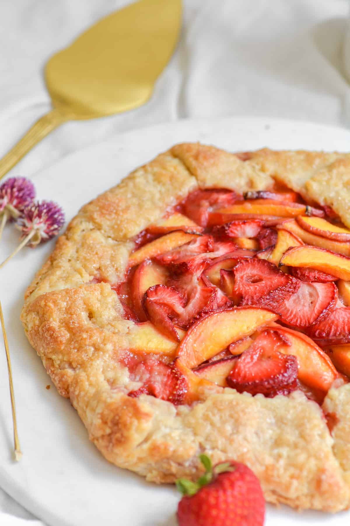 Vegan strawberry peach galette on a round board.