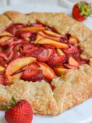 Vegan strawberry peach galette tart on a white round board.