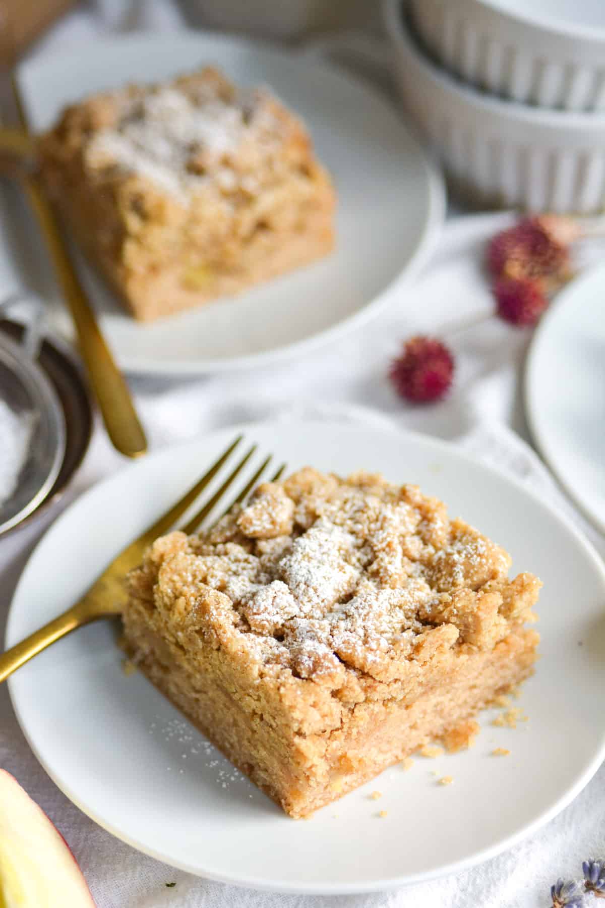 Vegan Applesauce Cinnamon Crumb Cake on a white plate with a gold fork.
