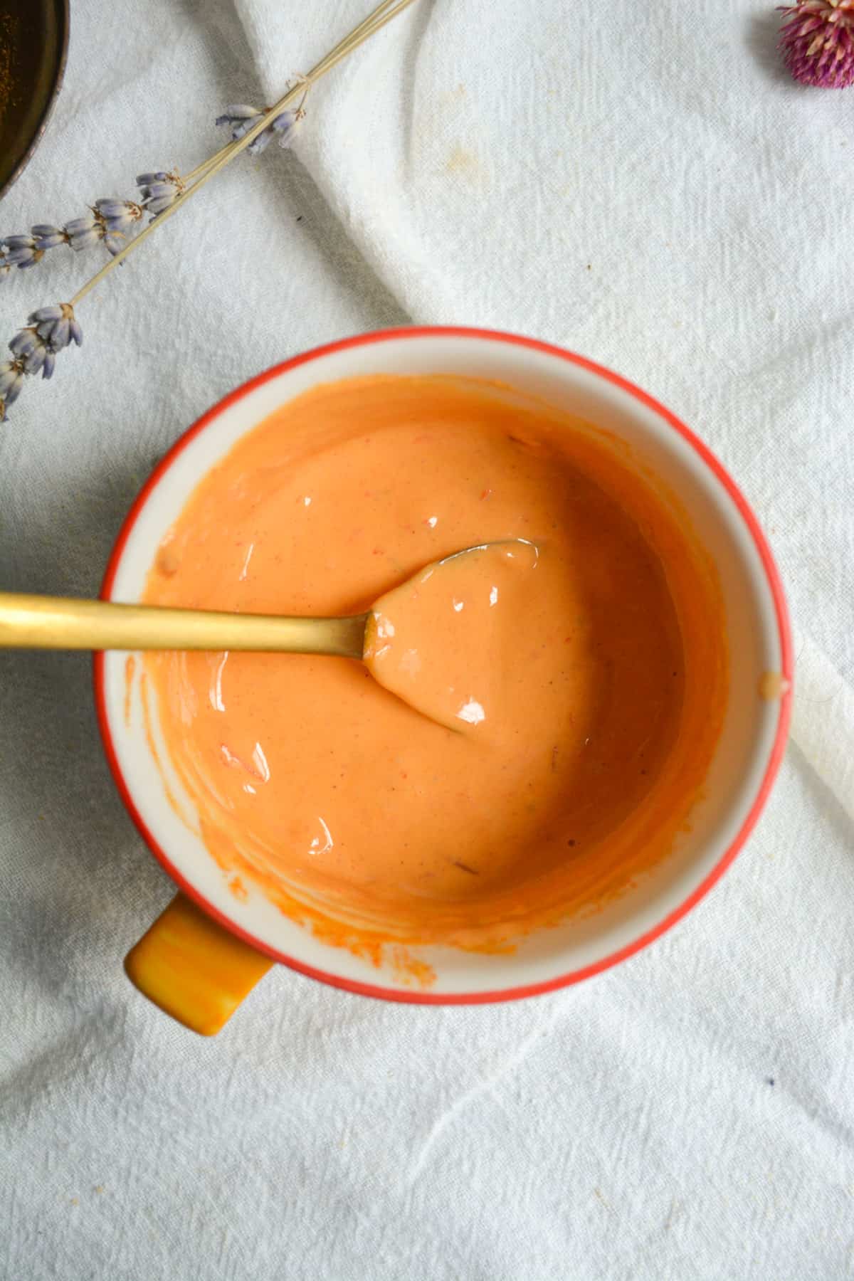 harissa tahini sauce in a small dish with a gold spoon.