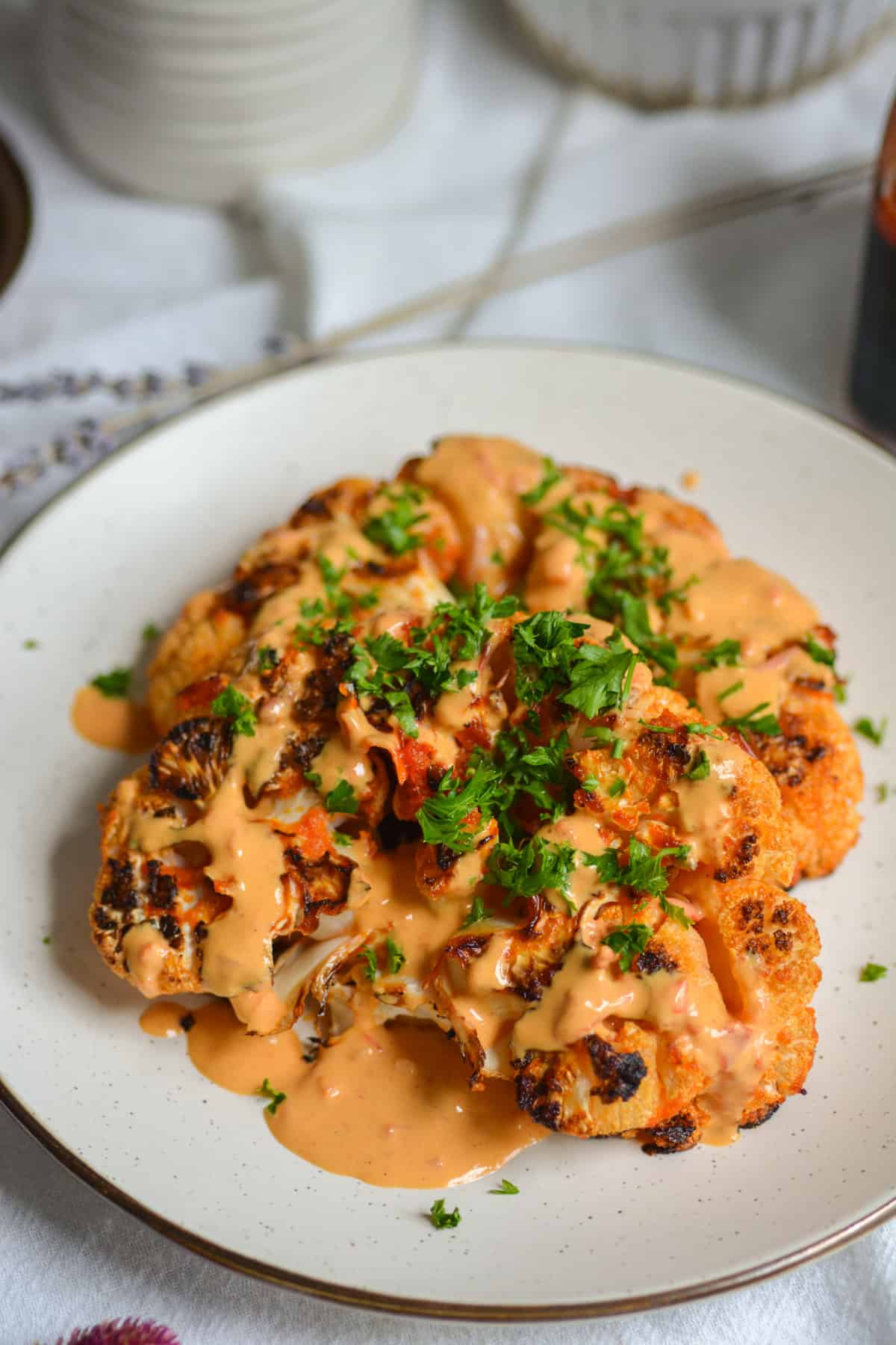 Vegan Harissa Butter Roasted Cauliflower Steaks on a plate topped with harissa tahini sauce