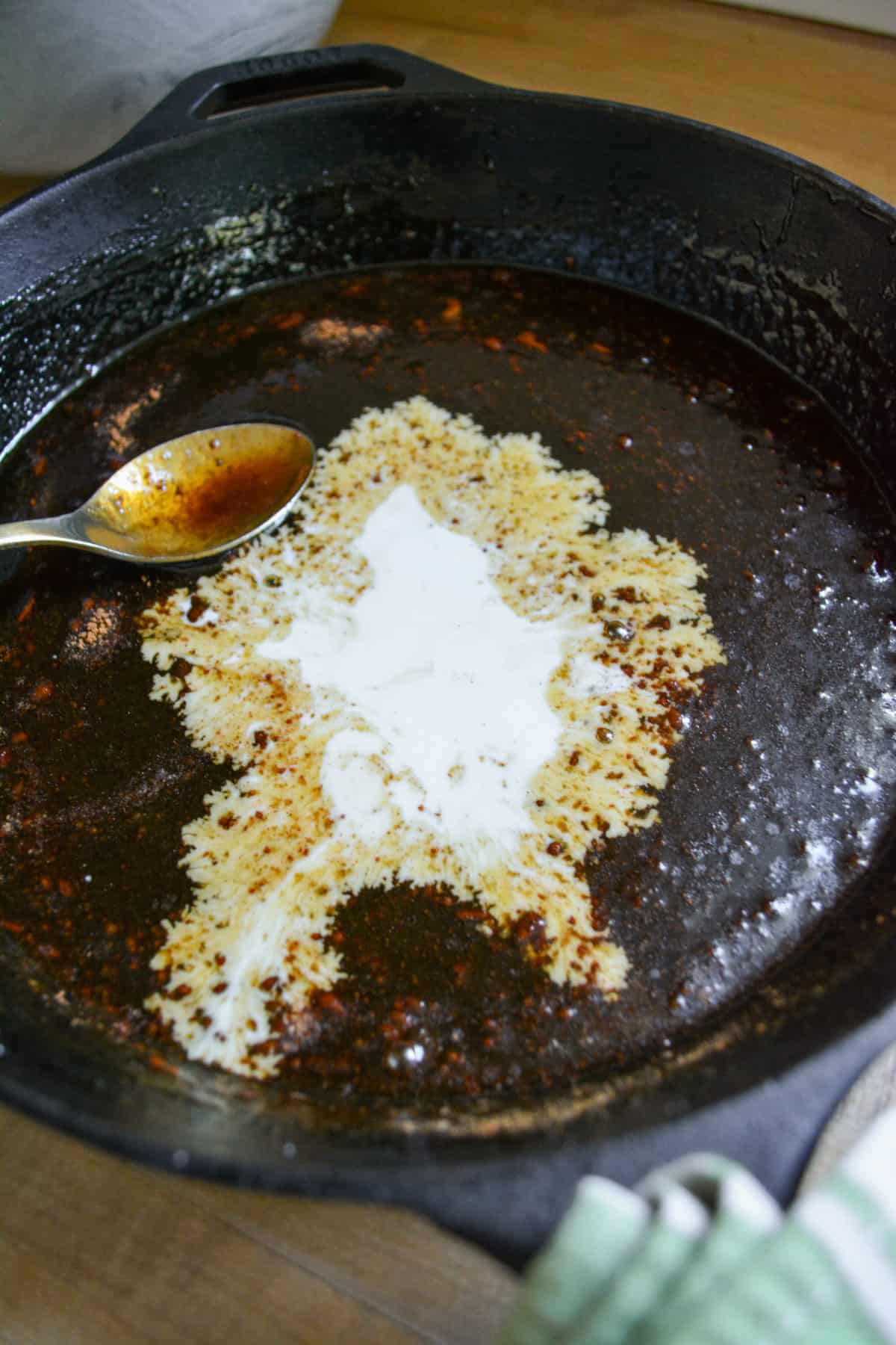 Cornstarch slurry added to the caramel in a black pan.