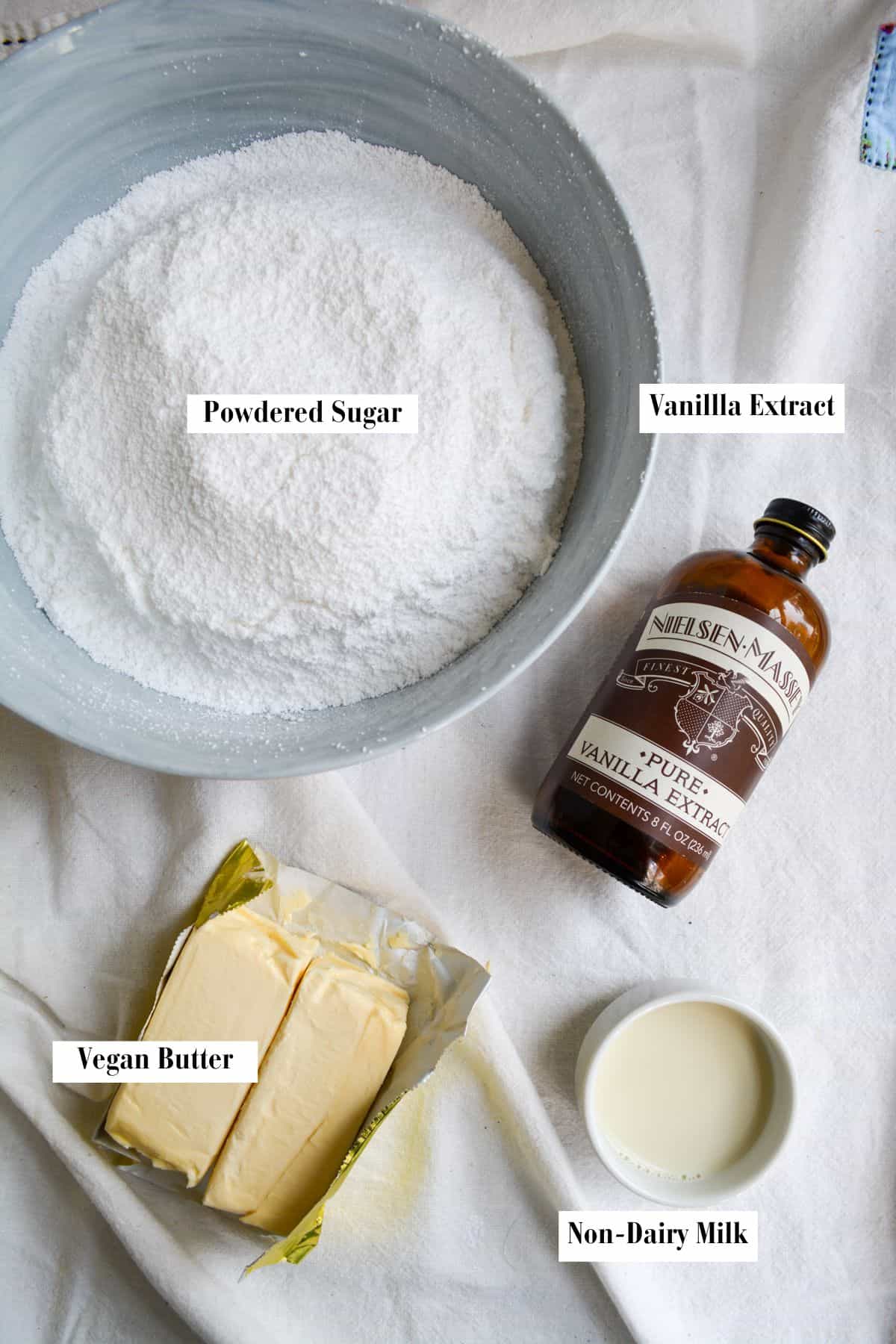 Overhead photo of vegan butter, powdered sugar, vanilla extract and non-dairy milk.