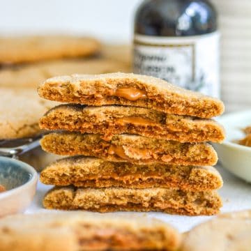 A stack of Vegan Biscoff Stuffed Cookies broken in half to show their molten interior.