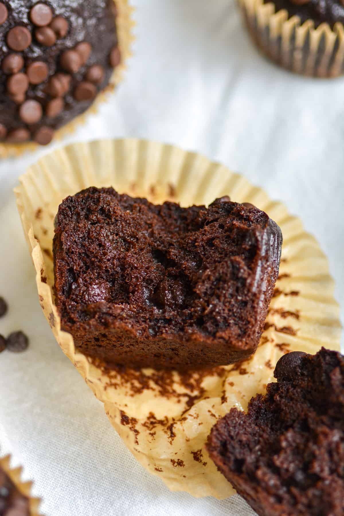 A Vegan Double Chocolate Banana Bread Muffin broken open on a muffin liner.
