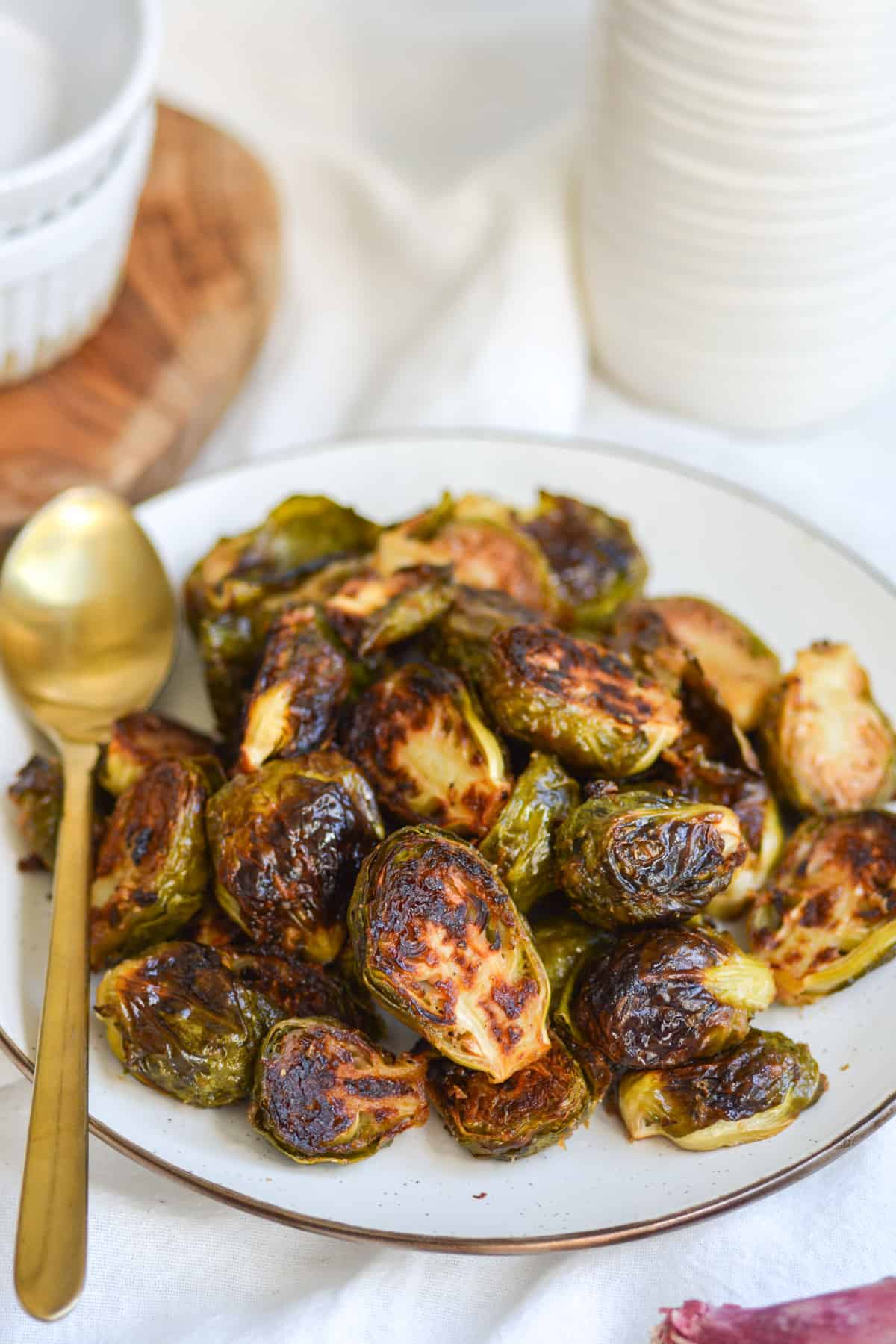 A plate full of Vegan Maple Dijon Mustard roasted Brussels Sprouts with a gold spoon.