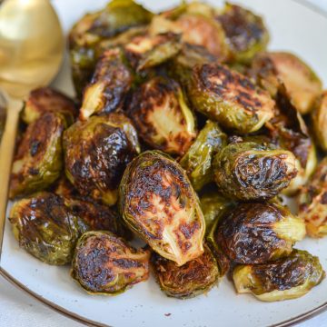 Close up on Vegan Maple Dijon Mustard Roasted Brussels sprouts on a tan plate.