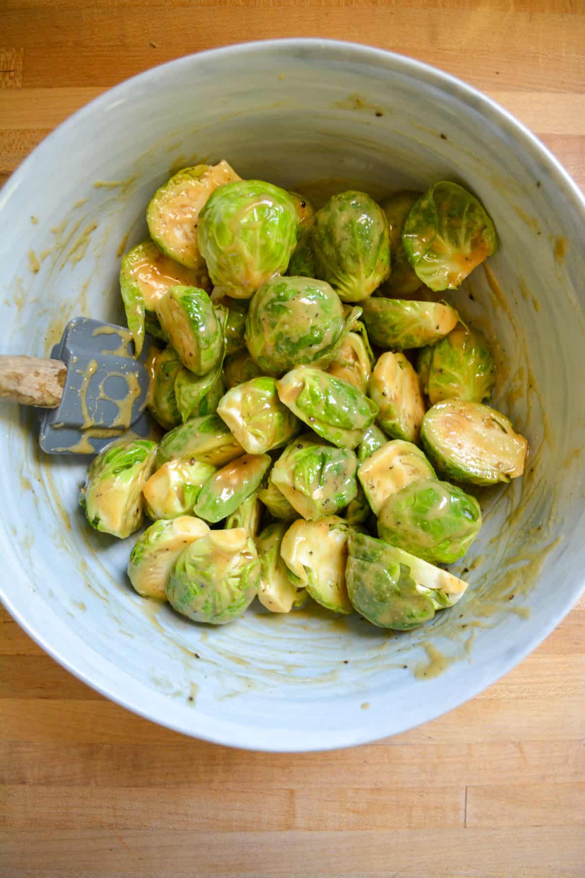 Brussels sprouts tossed in the sauce in a marble bowl.