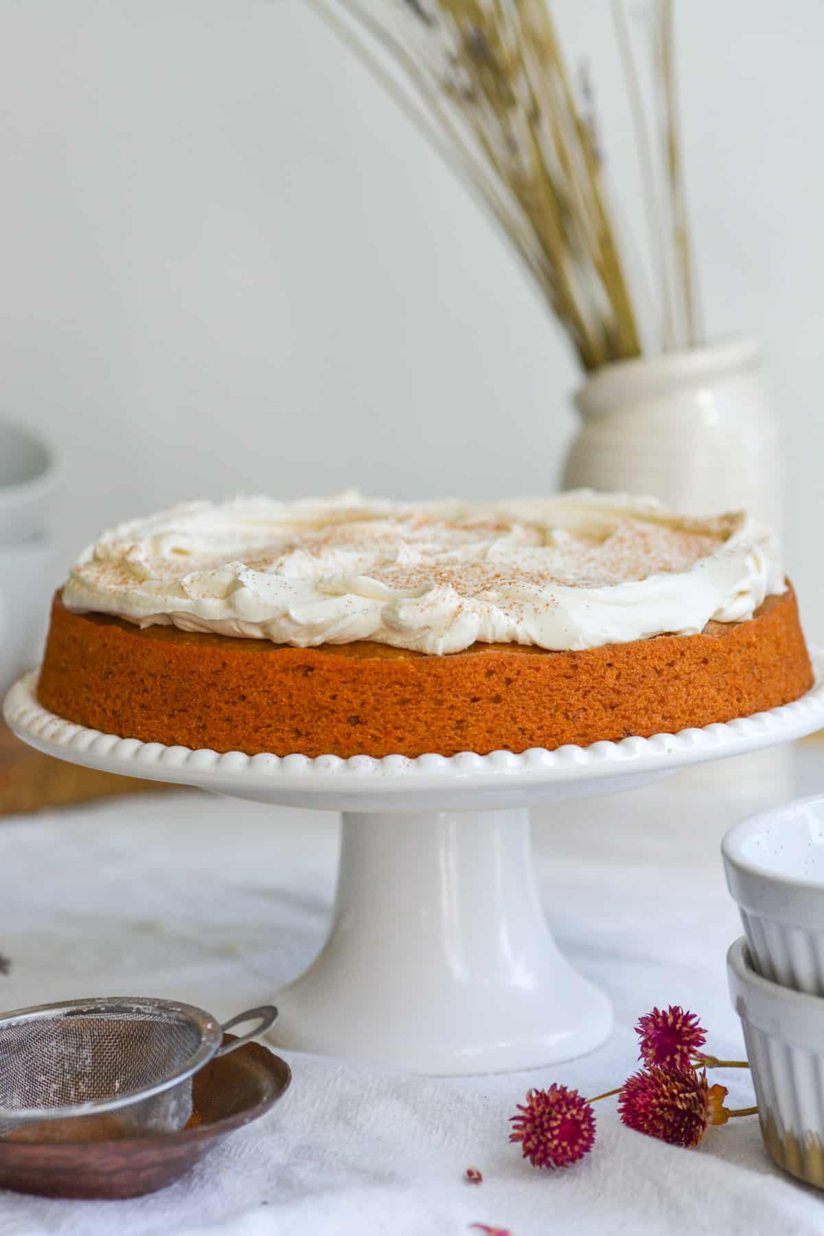 The frosted Vegan Maple Sweet Potato Cake on a white cake stand.