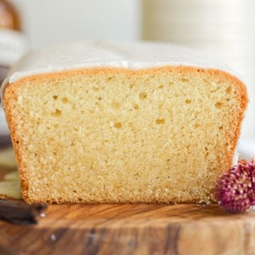 A close-up of the cross-section of a Vegan Vanilla Pound Cake loaf on a wooden board.