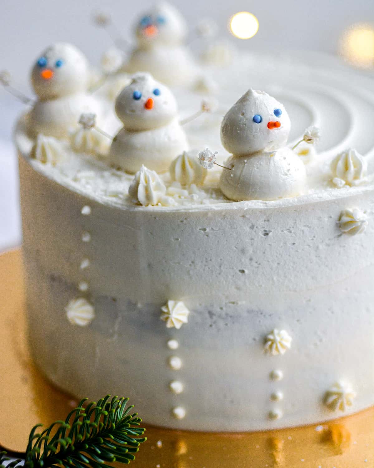 A cake frosted with vegan frosting with piped snowmen on top.