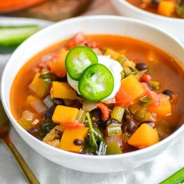 Black bean butternut squash soup in a white bowl topped with sour cream.