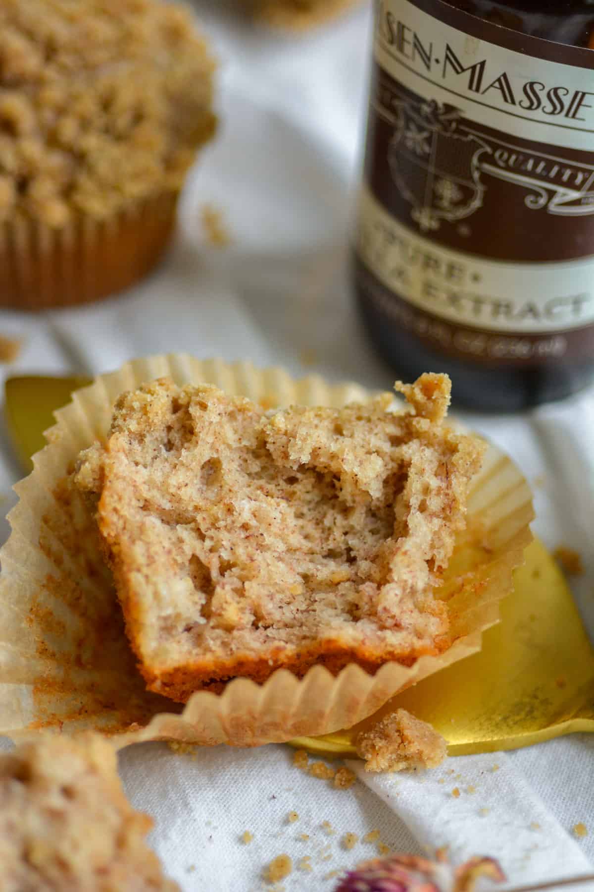 Broken open Vegan Banana Sour Cream Coffee Cake Muffin on top of its paper wrapper.