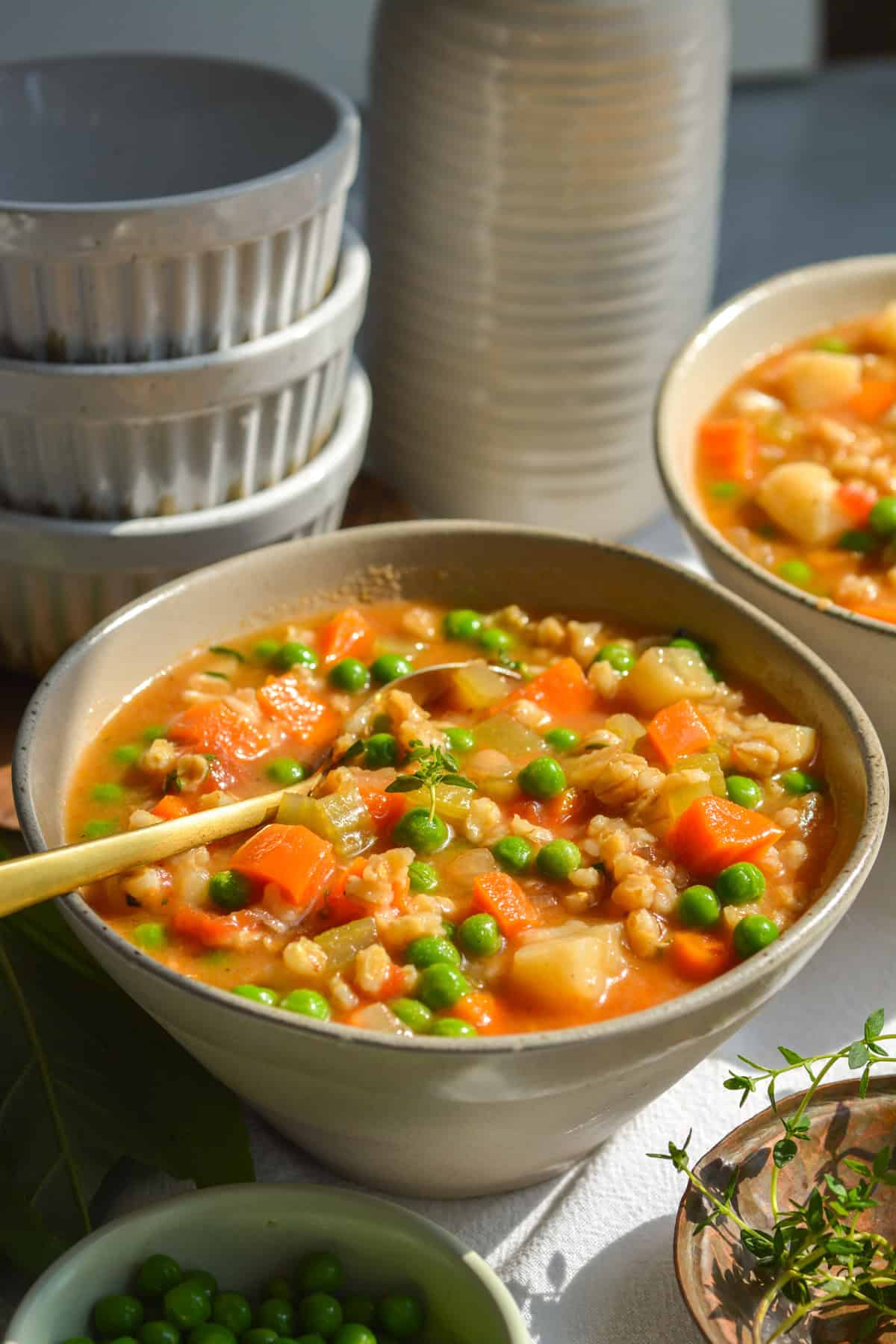 Two bowls of vegan barley vegetable soup in bowls on a linen cloth.