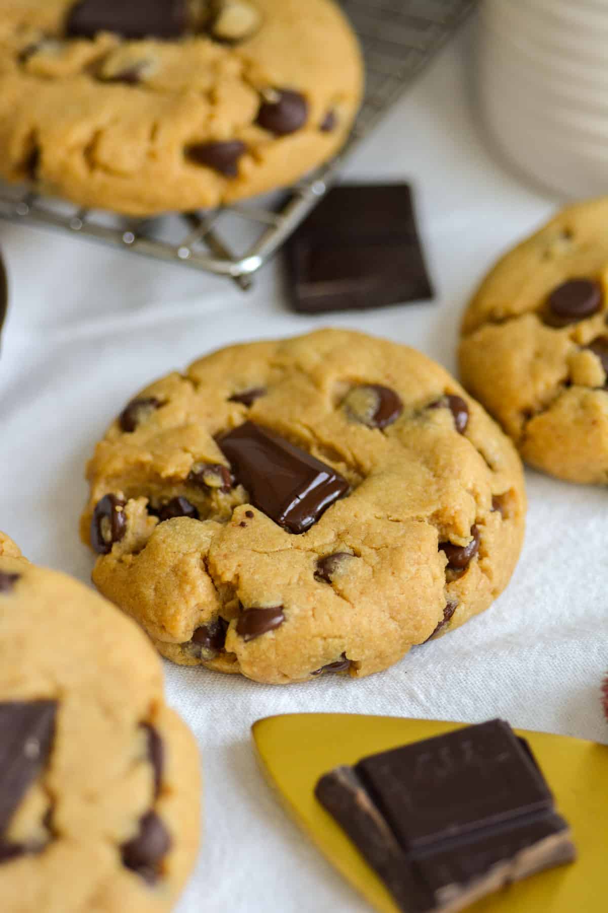 Vegan Peanut Butter Chocolate Chip Cookies on a white cloth with chocolate chunks in the scene.