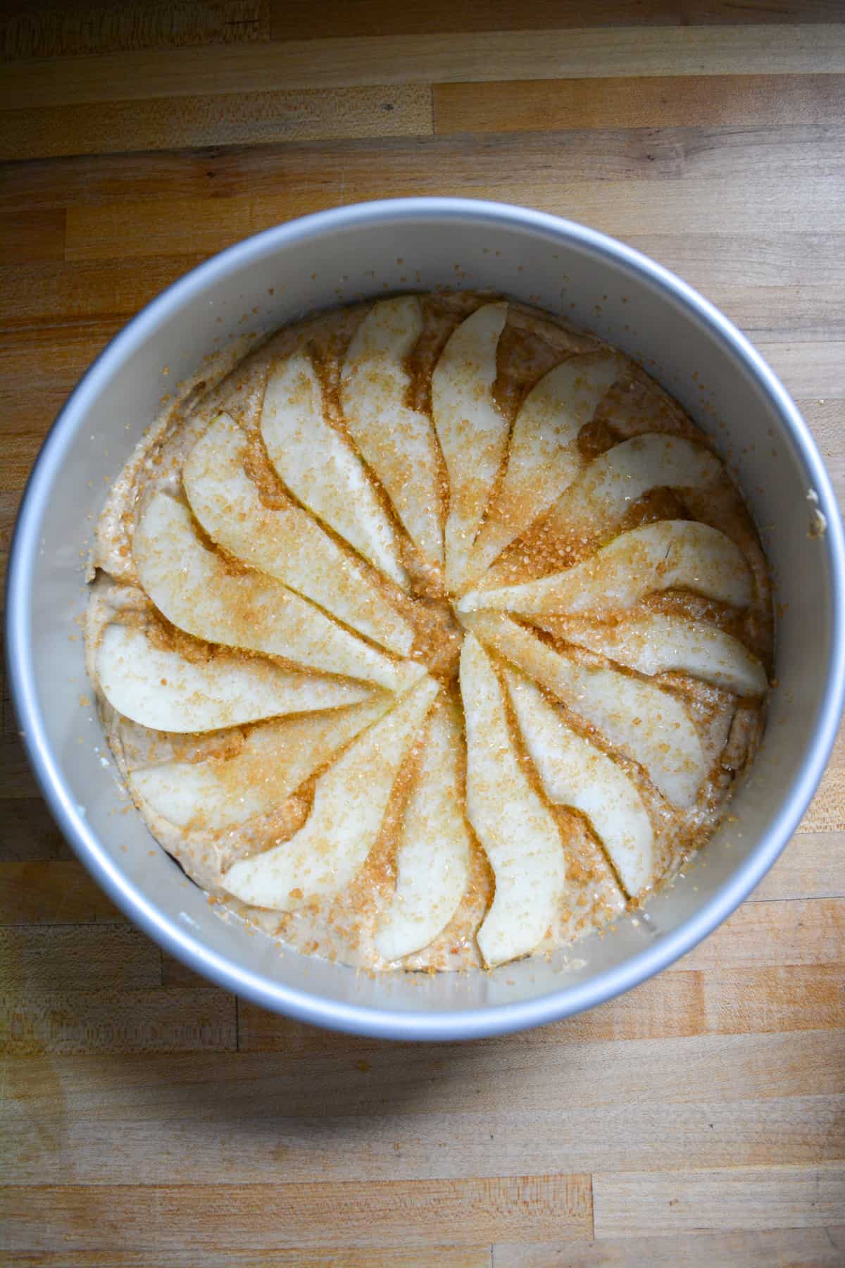 Photo of cake batter with pears in a circle on top ready to be baked.
