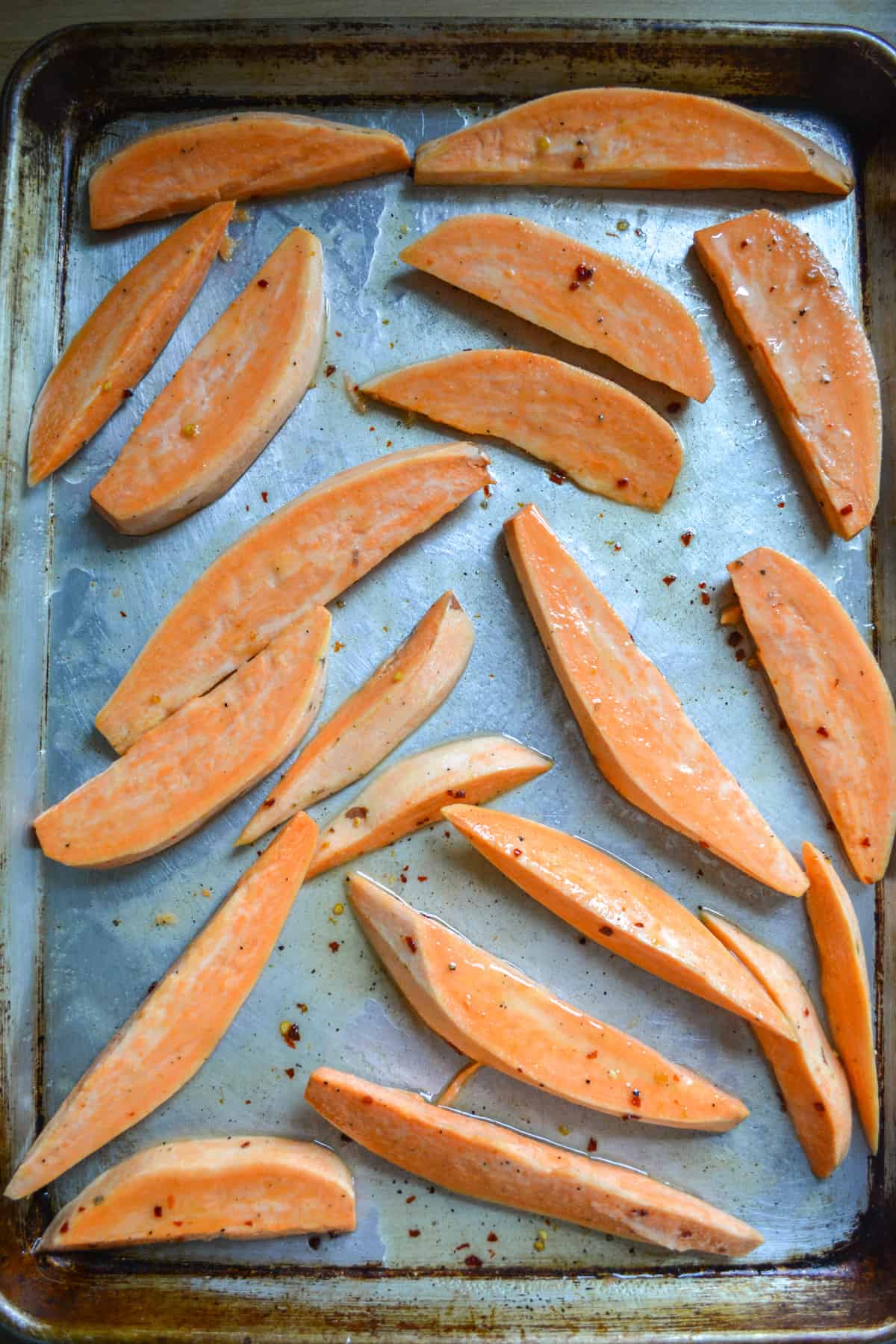 Sweet potato wedges covered in hot honey butter on a baking sheet.