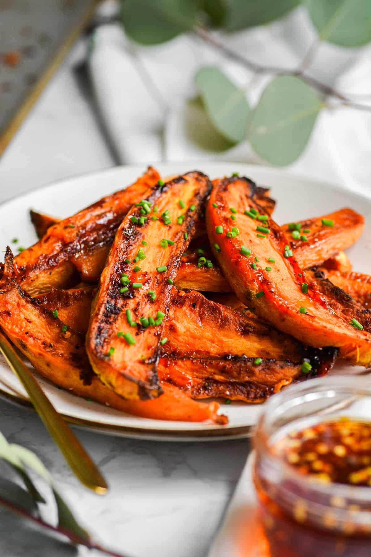 A plate with Roasted Sweet Potatoes with Hot Honey Butter topped with chives on it.