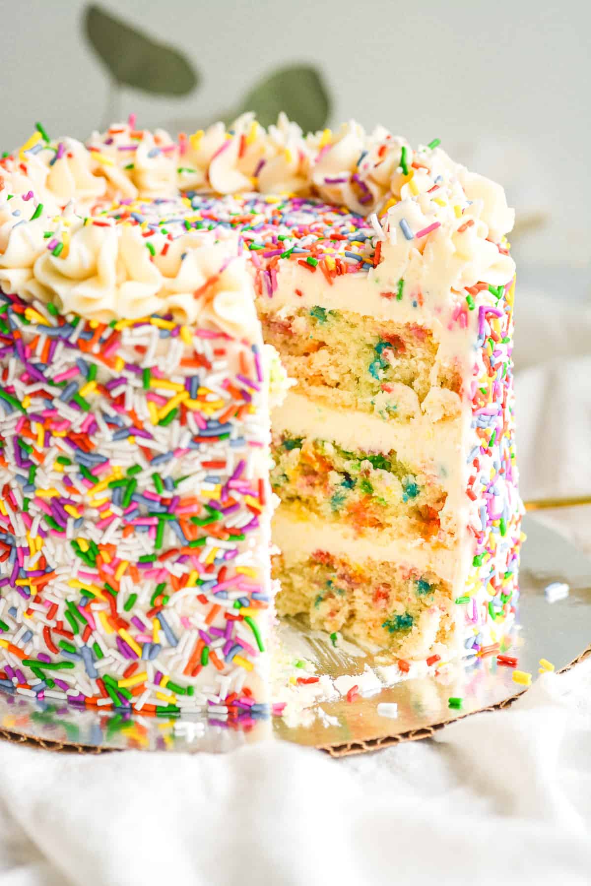 Vegan Funfetti cake with a slice taken out of it to see the cross section.
