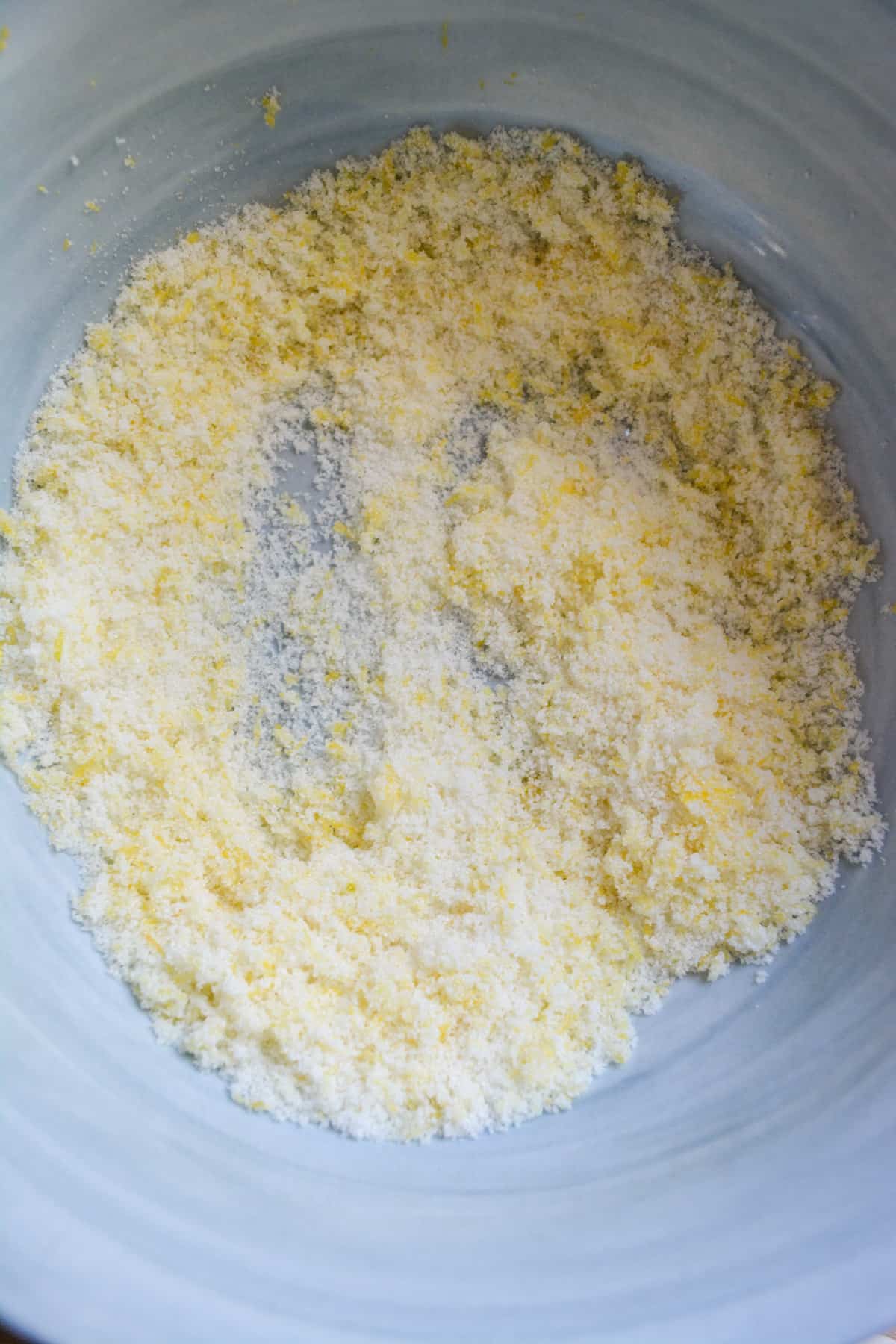 Granulated sugar and lemon zest rubbed together in a marble bowl.