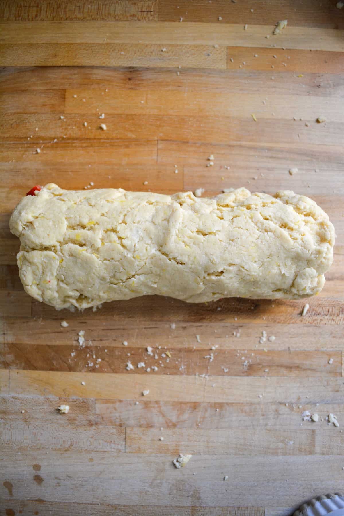 Scone dough rolled into a log on a wooden surface.