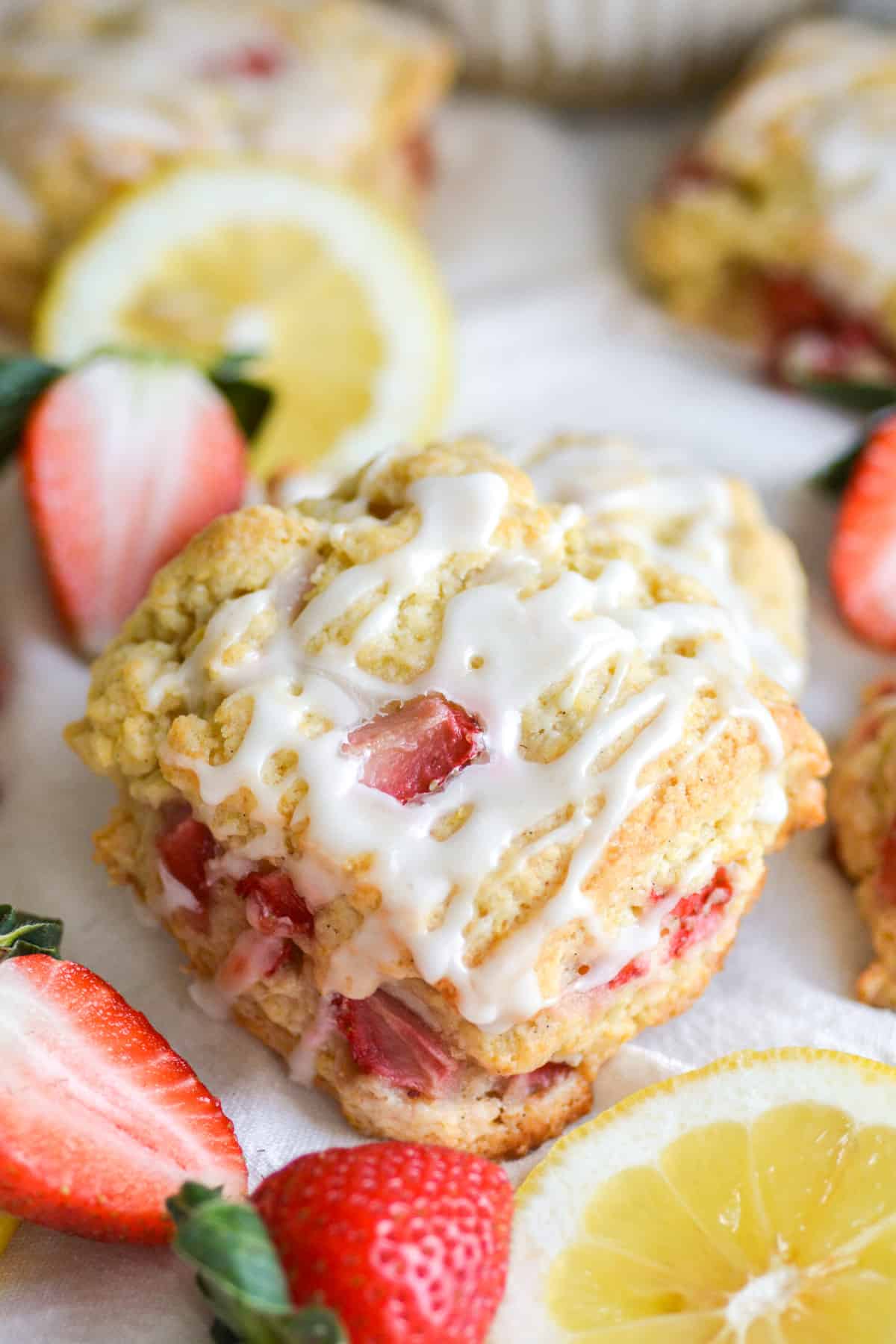 Vegan Lemon Strawberry Scones on a white cloth with strawberries and sliced lemon in the scene.