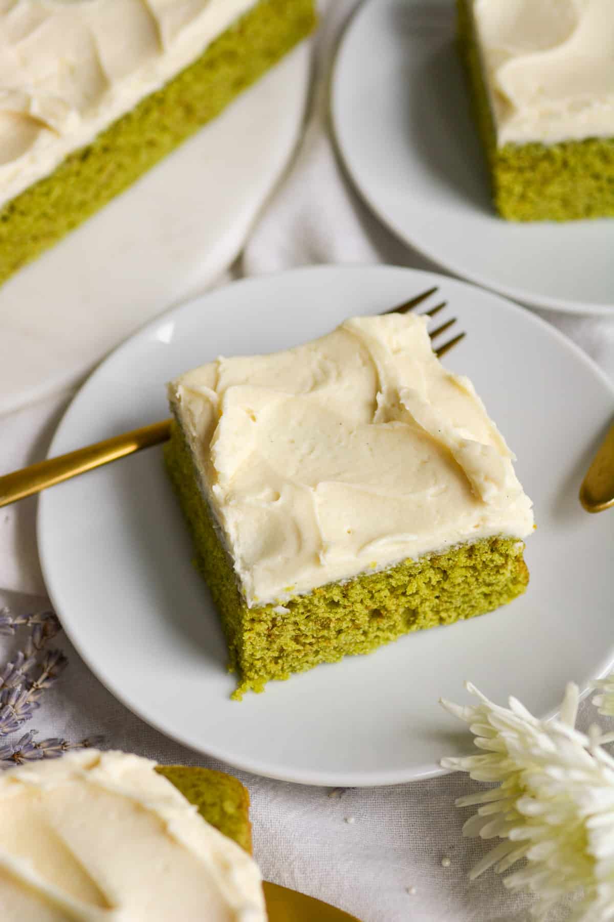 Vegan Matcha Cake on a white plate with a gold fork.