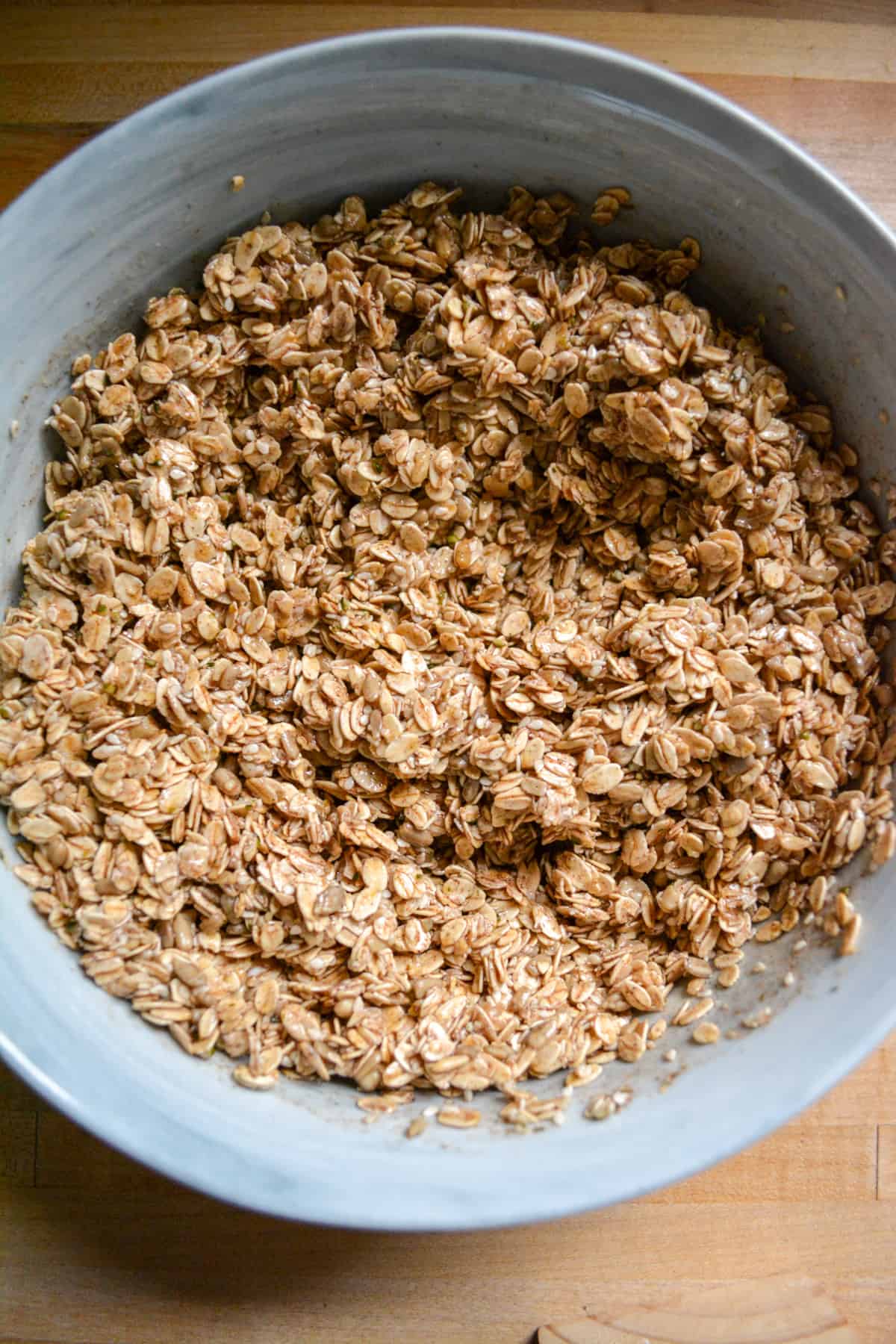 Oats mixed together with the wet ingredients in a mixing bowl.
