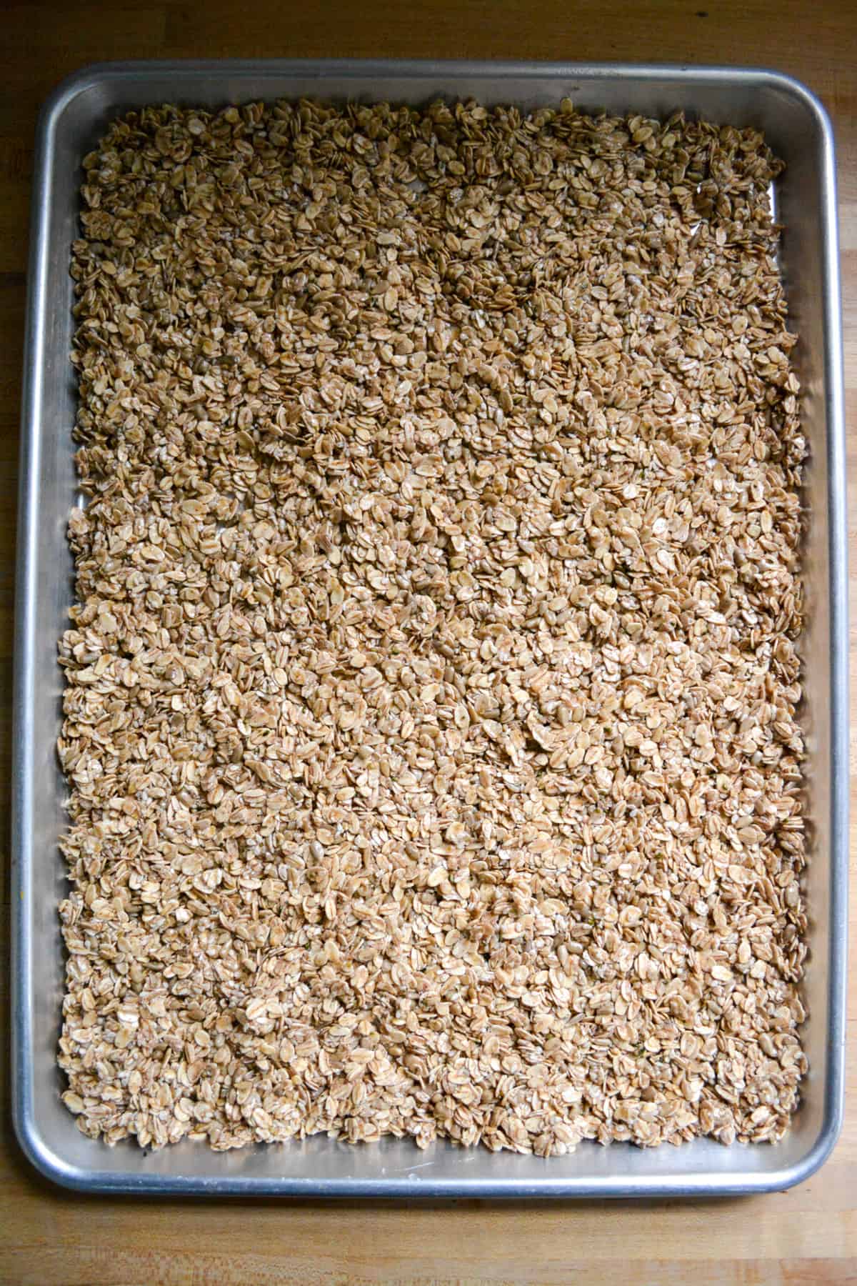 Homemade cinnamon granola pressed onto a baking sheet.
