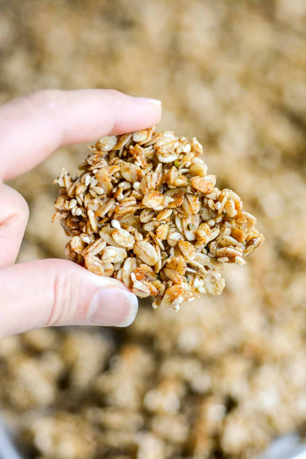 Hand holding a large Homemade Cinnamon Granola cluster.