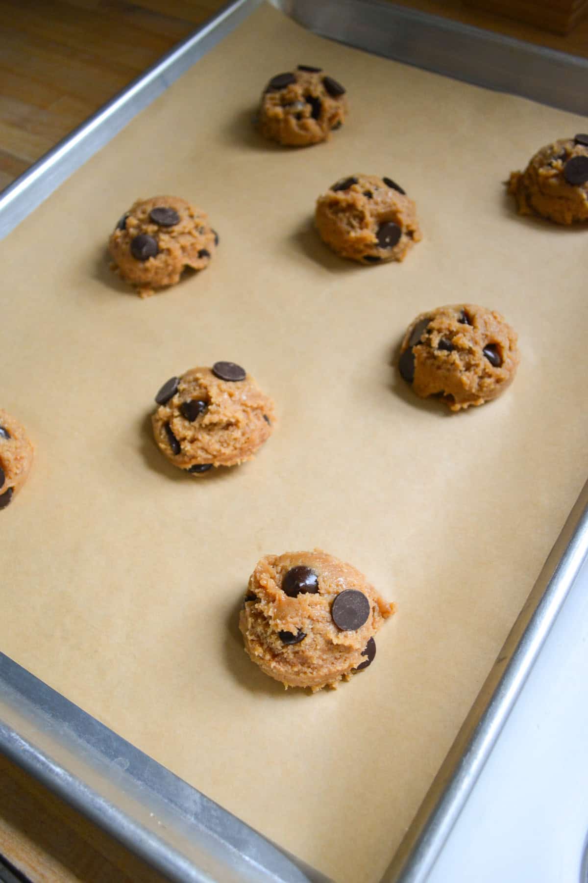 Cookie dough scooped onto a parchment lined baking sheet.