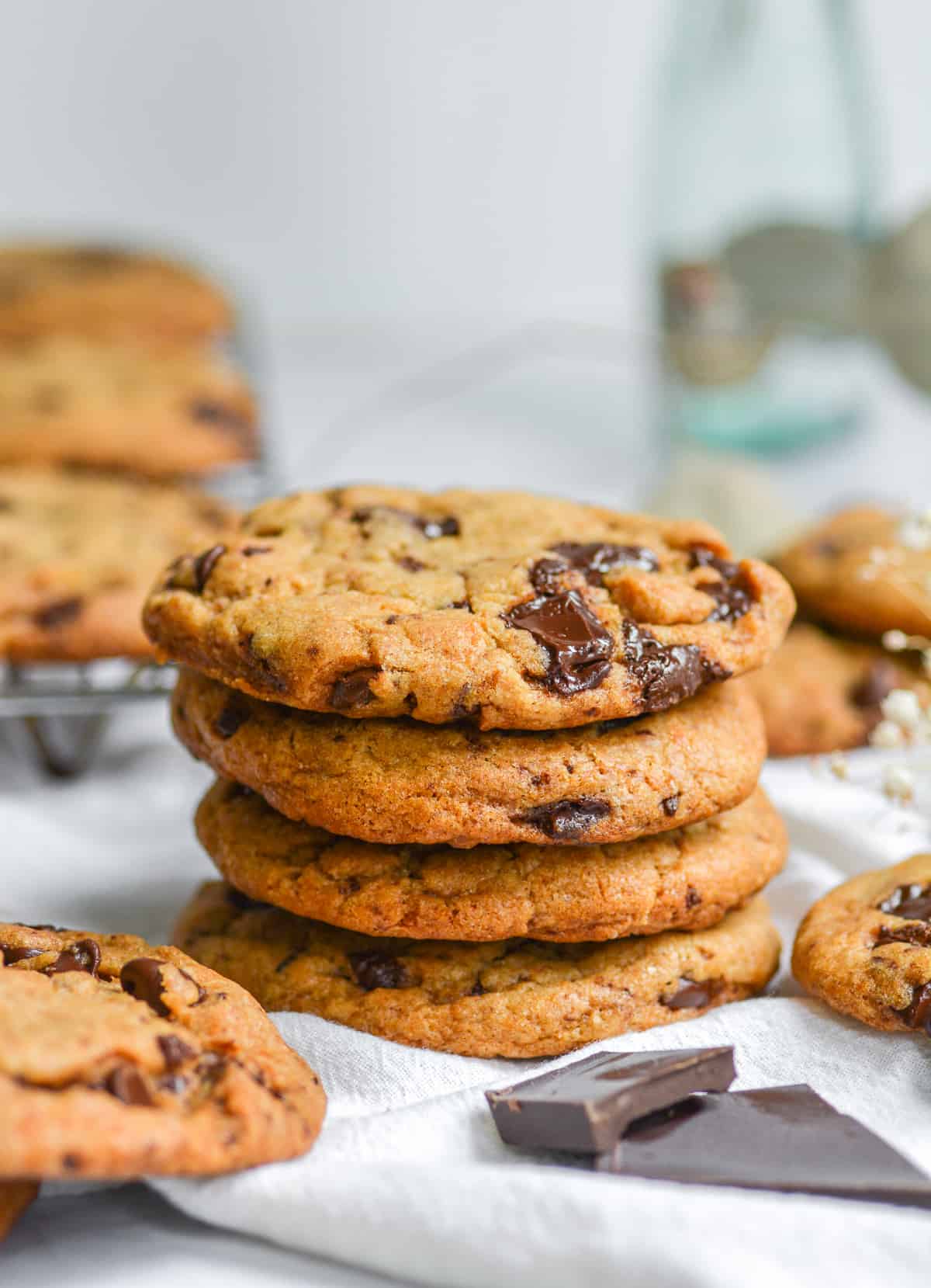 4 Vegan Banana Chocolate chip cookies stacked on top of each other on a white cloth.
