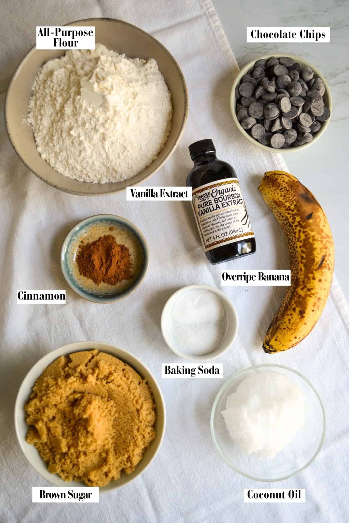 Cookie ingredients in small bowls on a linen surface.
