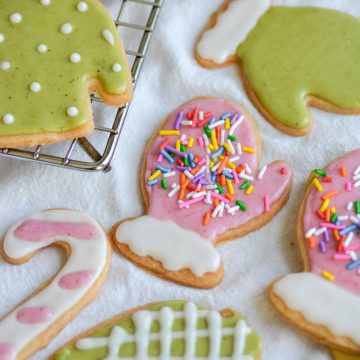 Dairy-Free Vegan Cut-Out sugar cookies decorated with green and pink icing on a white cloth.