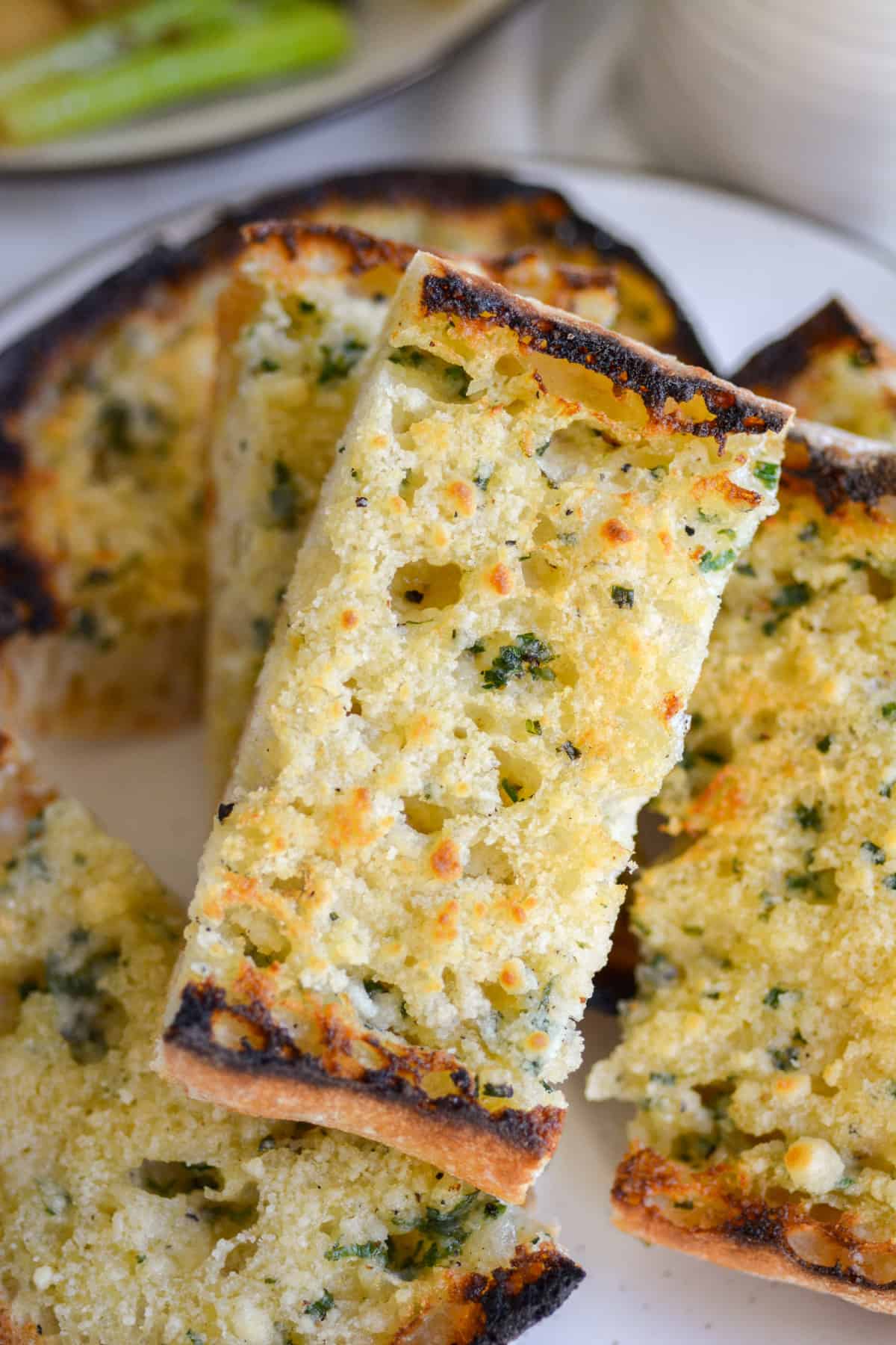 Vegan Cheesy Garlic Bread on a plate with other slices of garlic bread.