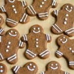 Vegan Gingerbread Men decorated with royal icing on a lined baking sheet.