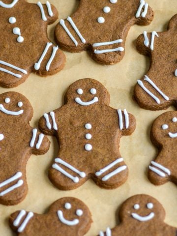 Vegan Gingerbread Men decorated with royal icing on a lined baking sheet.